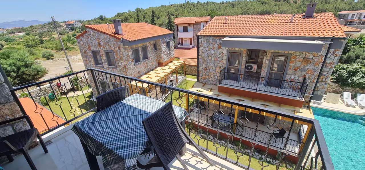 Villa Nora balkonundan taş mimari, bahçe ve havuz görünümü