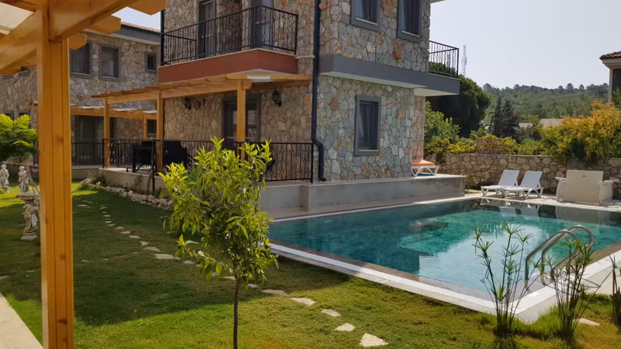 Villa Nora Datça’nın doğal taş yapıları, yeşil bahçesi ve turkuaz yüzme havuzu